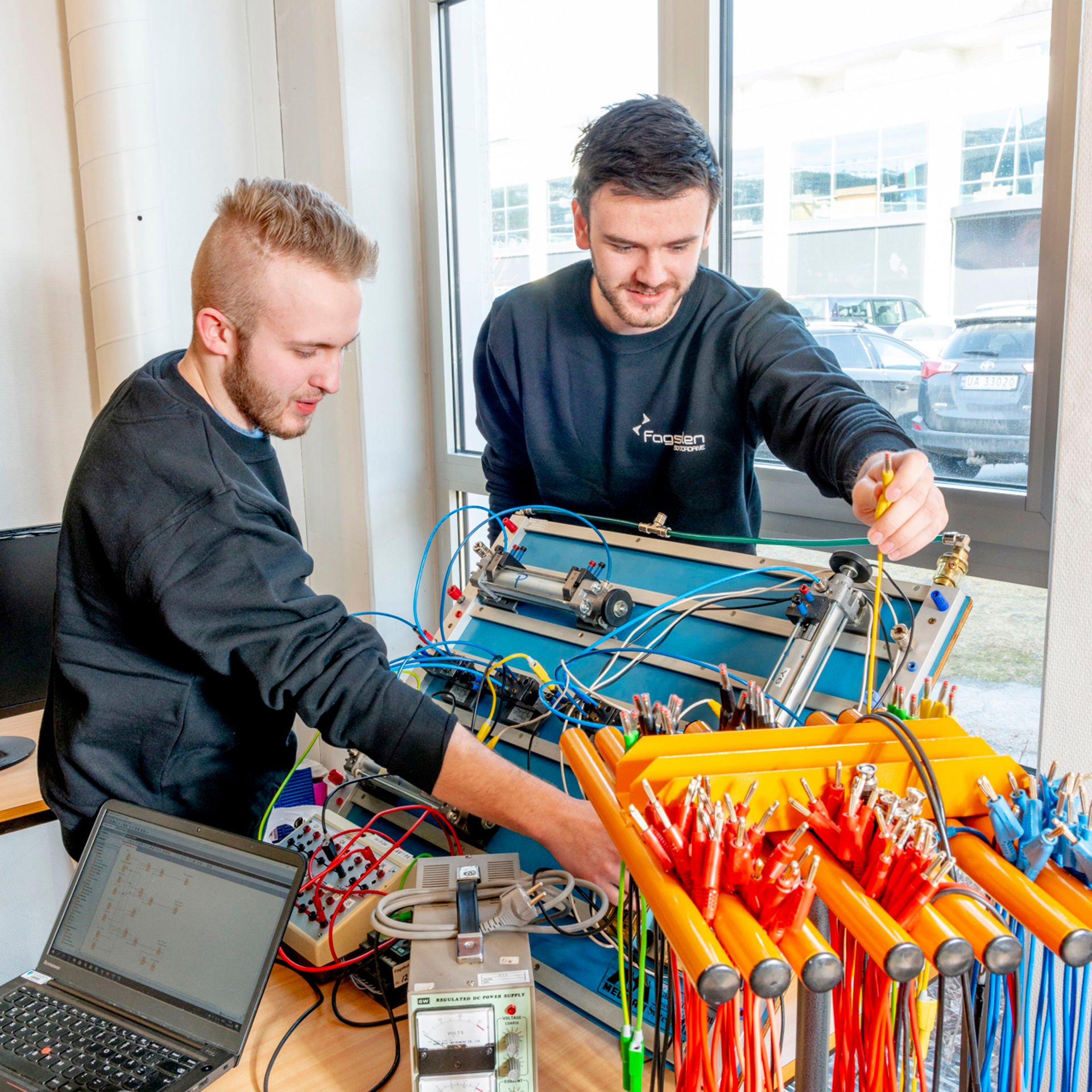 Bildet viser to studentar som koplar leidningar