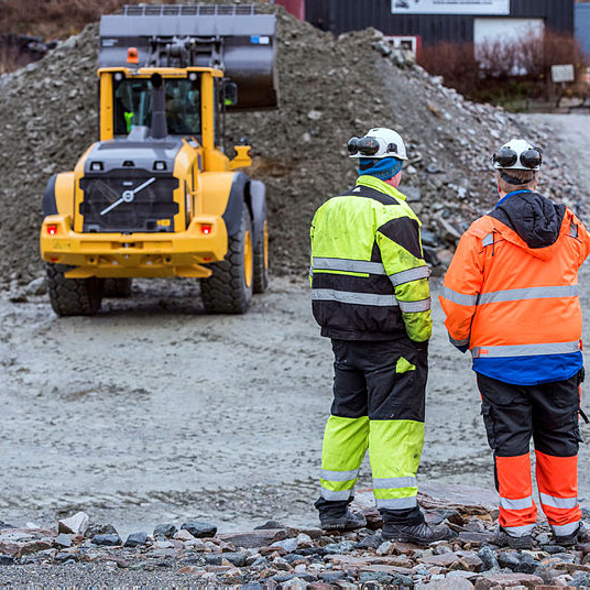 Bildet viser to personar i arbeidsklede på eit anleggsområde